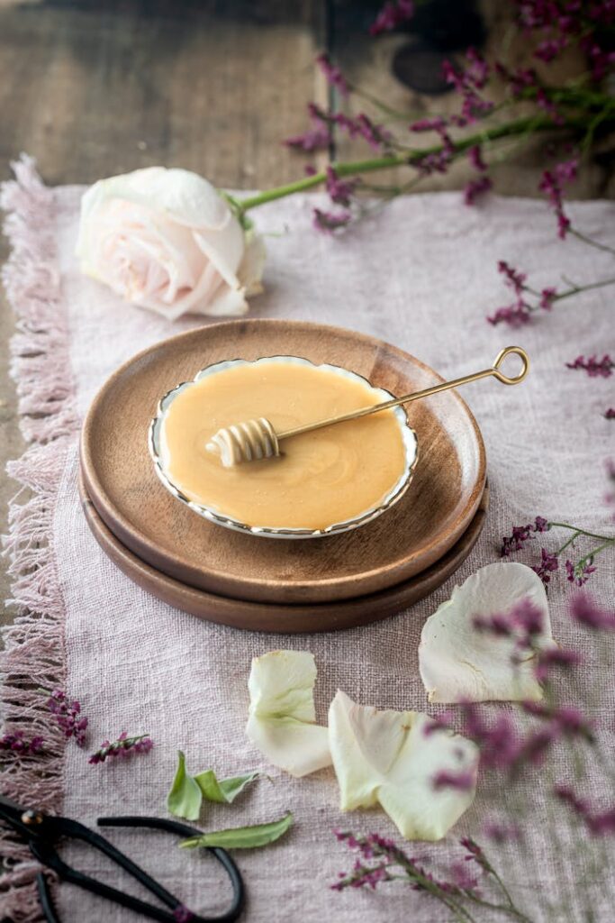 A close-up of honey in a dish with fresh flowers and rustic elements.